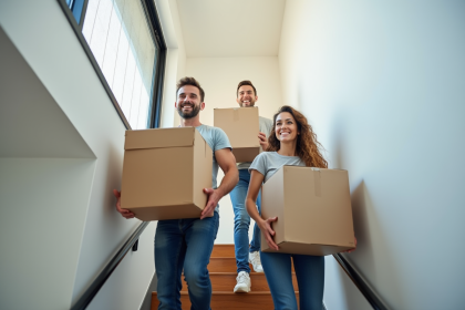 Trois adultes portant des cartons dans un appartement moderne
